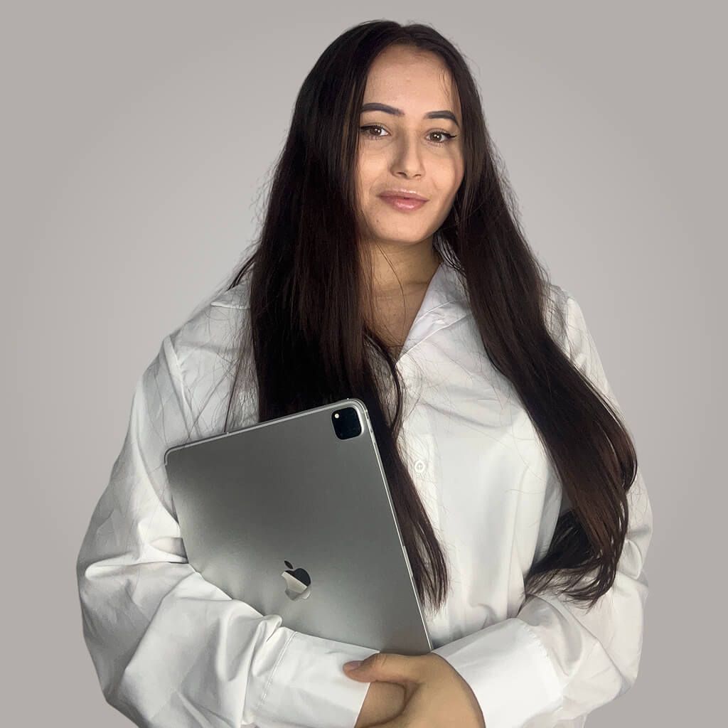 Nagy Noémi szerepel a képen egy szürke fal előtt kezében egy okos eszközt tart